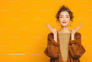 Cheerful Young Woman with Curly Hair in Warm Sweater on Yellow Background