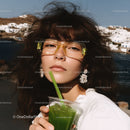 Fashionable Young Woman Sipping Green Juice by the Seaside