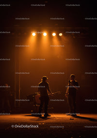 Musicians rehearsing under warm orange stage lights