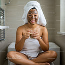 Happy Woman Relaxing with Facial Mask and Cup in Bathroom