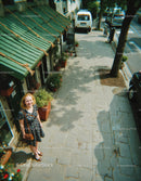 Smiling Woman Standing on City Sidewalk with Flanking Flower Pots