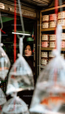 Young woman peeks from doorway of traditional market shop
