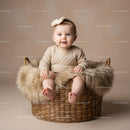 Adorable baby sitting in cozy basket with fluffy blanket