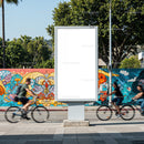 Urban cyclists passing blank billboard with colorful mural