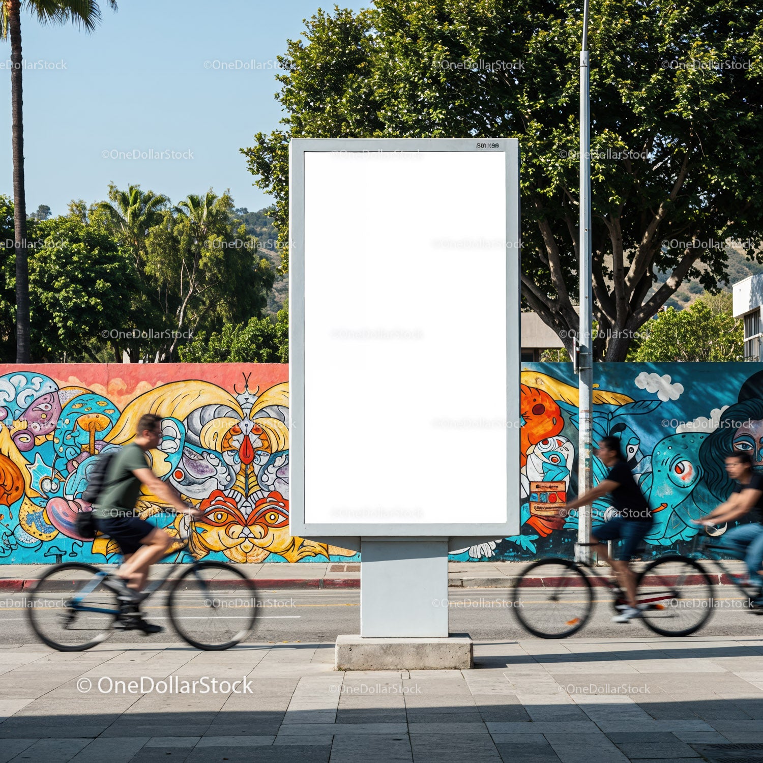 Rowerzyści mijający pusty billboard z kolorowym muralem