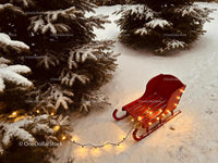 Red Sleigh with Warm Lights by Snowy Pine Trees