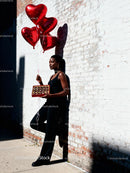 Woman with Heart Balloons and Chocolates by Brick Wall