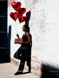 Woman with Heart Balloons and Chocolates by Brick Wall