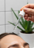 Clear Skin with Serum Dropper Over a Woman's Forehead in a Cosmetology Setting