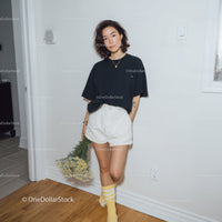 Young Woman in Casual Black T-Shirt and White Shorts Holding Flowers