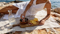 Woman enjoying fresh figs and citrus on rocky shore