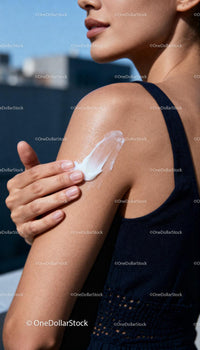 Woman applying moisturizing cream on shoulder outdoors