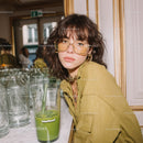 Fashionable Young Woman with Glass of Green Juice in Modern Cafe