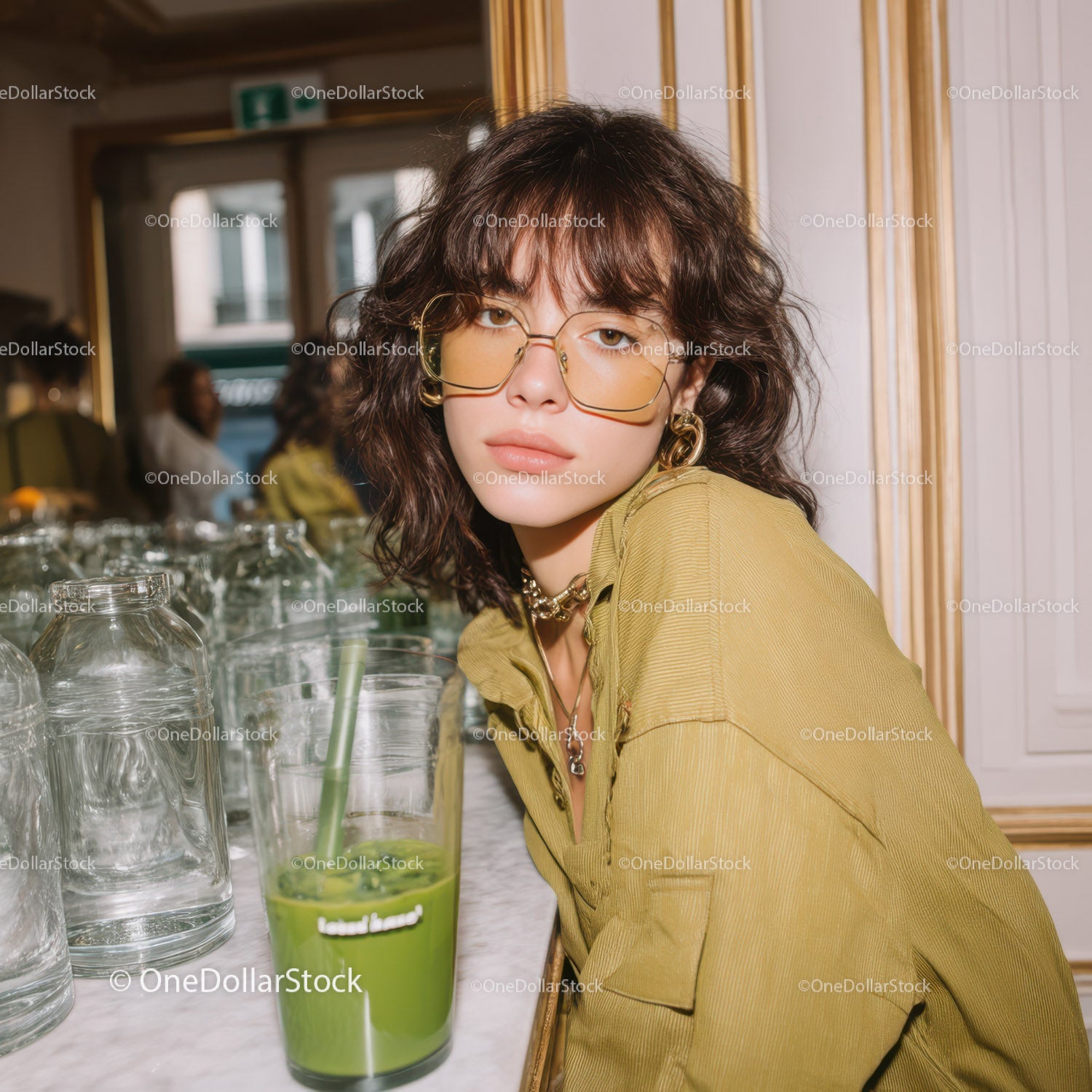 Fashionable Young Woman with Glass of Green Juice in Modern Cafe
