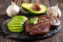 Juicy Grilled Steak with Fresh Avocado and Garlic on Rustic Board
