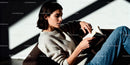 Young woman absorbed in book on cozy sofa