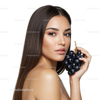 Elegant Woman with Long Brown Hair Holding Black Grapes in Studio