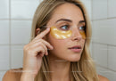 Young Woman with Eye Gel Patches Applying Skincare Treatment in Bathroom