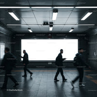 Commuters walking past blank digital billboard underground