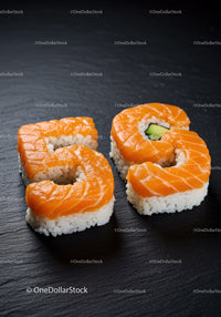 Salmon Sushi Rolls Shaped as Number 65 on Slate