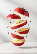 Sliced red apple floating with scattered seeds