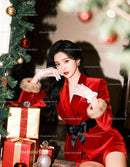 Elegant woman in red velvet outfit by Christmas tree