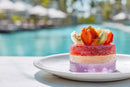 Colorful Layered Fruit Cake with Fresh Tropical Fruits on White Plate