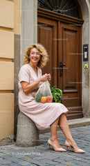 Smiling woman resting on stone with fresh groceries