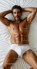 Fit man relaxing on bed wearing white briefs