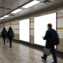 People walking past blank advertising panels in subway