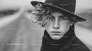 Young Man with Curly Hair and Black Hat in Monochrome Portrait
