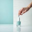 Elegant Woman Hand Applying Light Blue Nail Polish on White Background