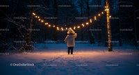Child exploring snowy forest under warm string lights