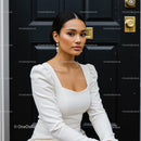 Elegant woman in white dress sitting by black door