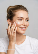 Beautiful Woman Applying Facial Moisturizer for Healthy Glowing Skin