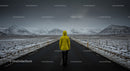 Lonely Traveler in Yellow Jacket on Snow-Covered Road