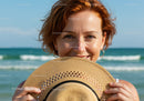 Smiling Woman at the Beach Holding Straw Hat with Ocean and Blue Sky