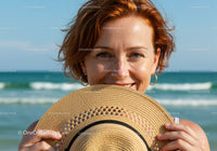 Smiling Woman at the Beach Holding Straw Hat with Ocean and Blue Sky
