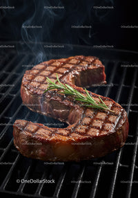 Grilled juicy steak with rosemary garnish on barbecue