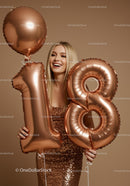 Smiling young woman holding 18th birthday balloons