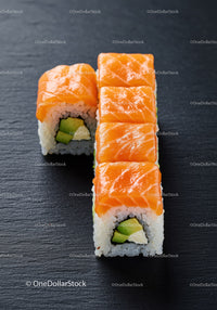Fresh salmon sushi rolls with avocado on black slate