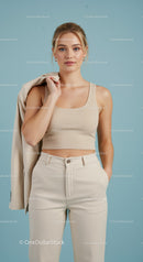 Elegant Young Woman in Beige Crop Top and Trousers Against Blue Background