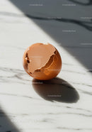 Cracked brown eggshell resting on marble surface