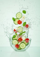 Fresh cucumber and tomato salad splashing in glass bowl