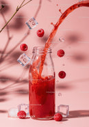 Refreshing raspberry juice pouring into glass bottle