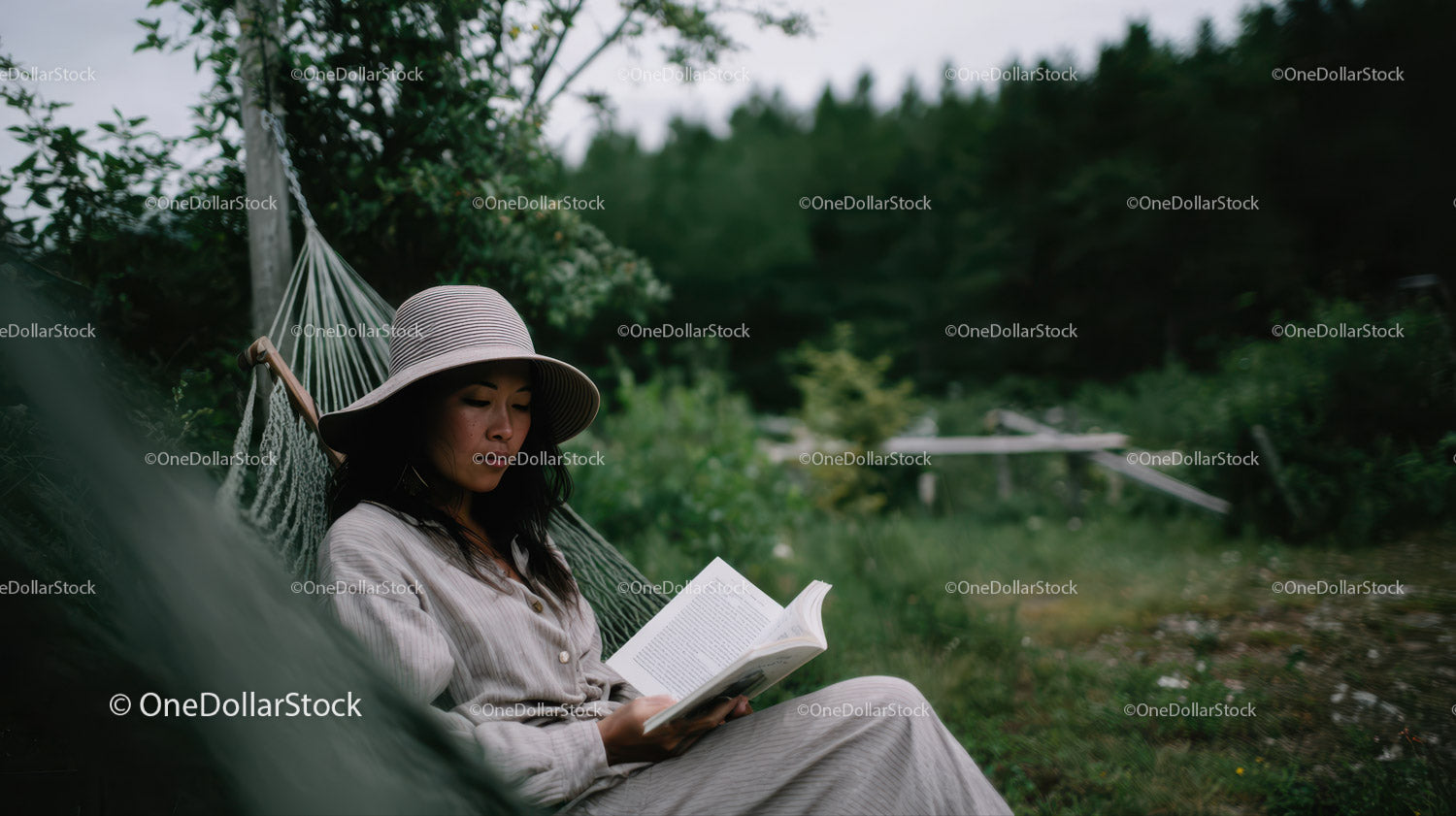 Woman Relaxing in Hammock Reading a Book in Green Nature