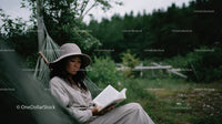 Woman Relaxing in Hammock Reading a Book in Green Nature