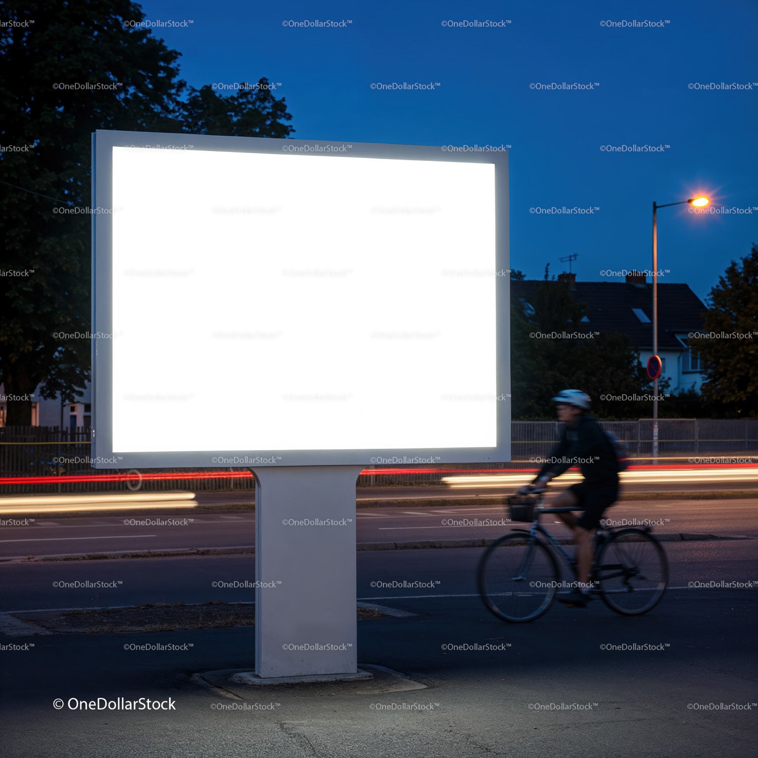 Rowerzysta przejeżdżający nocą obok oświetlonego, pustego billboardu
