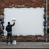 Man painting blank white rectangle on brick wall