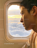 Passenger Gazing at Clouds and Sunset from Airplane Window